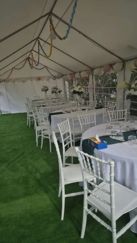 Interior de cort cu mese festive, flori albe, scaune albe și mochetă verde