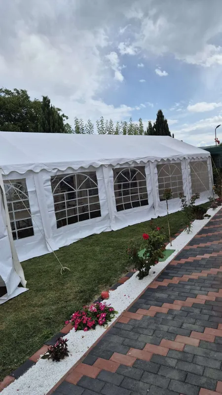Exterior de cort alb cu ferestre arcuite, lângă o alee și flori în grădină